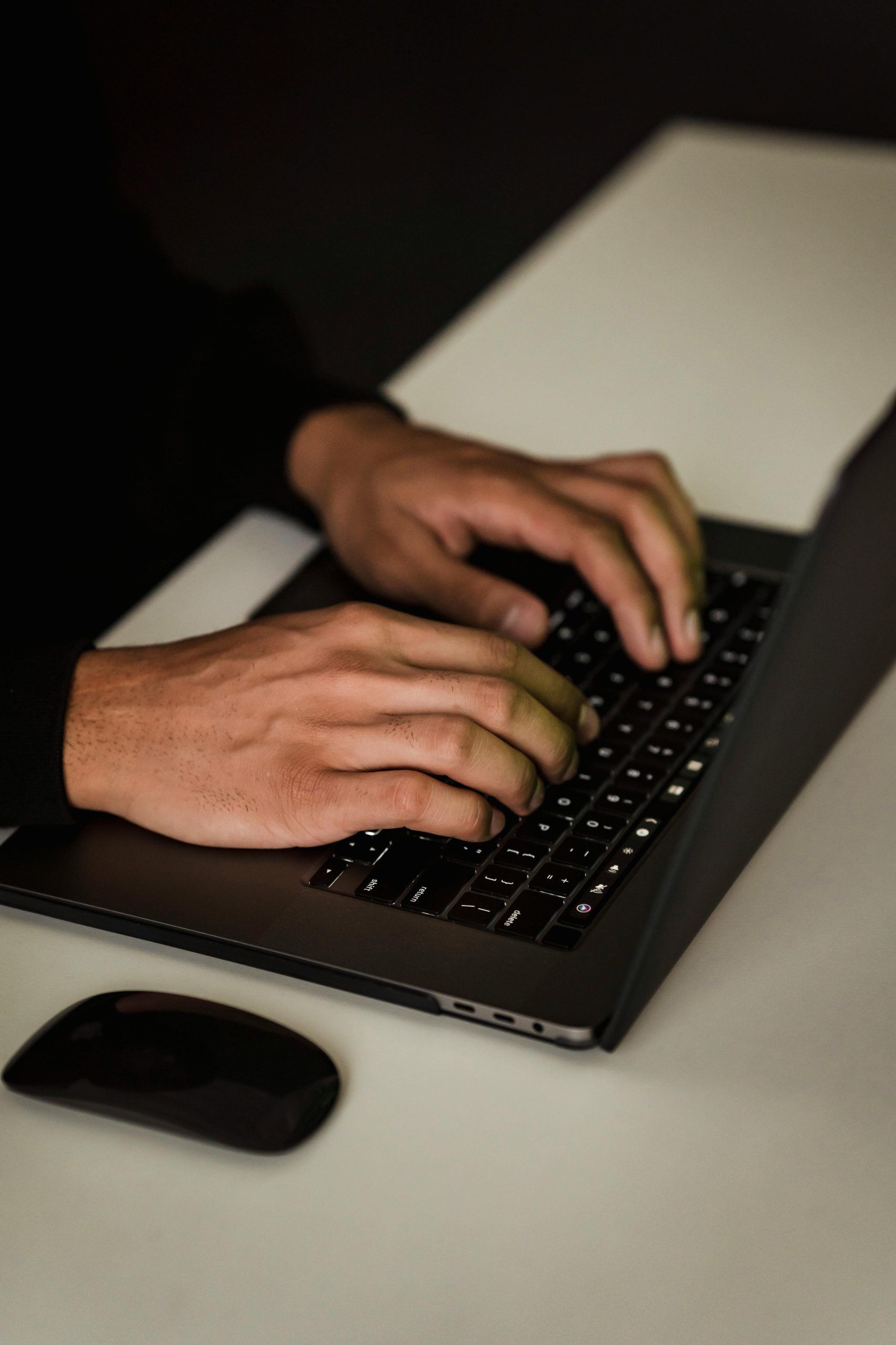 Close-up of hands typing on a laptop keyboard in a modern workspace.